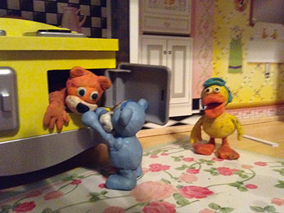 a blue bear helping a brown bear out of an over while a duck watches